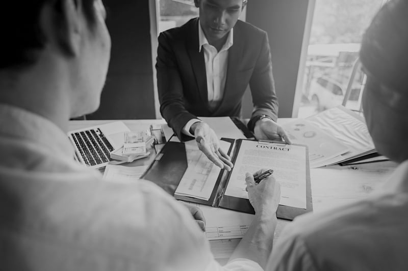 man and woman sign contract for businessman at cluttered desk