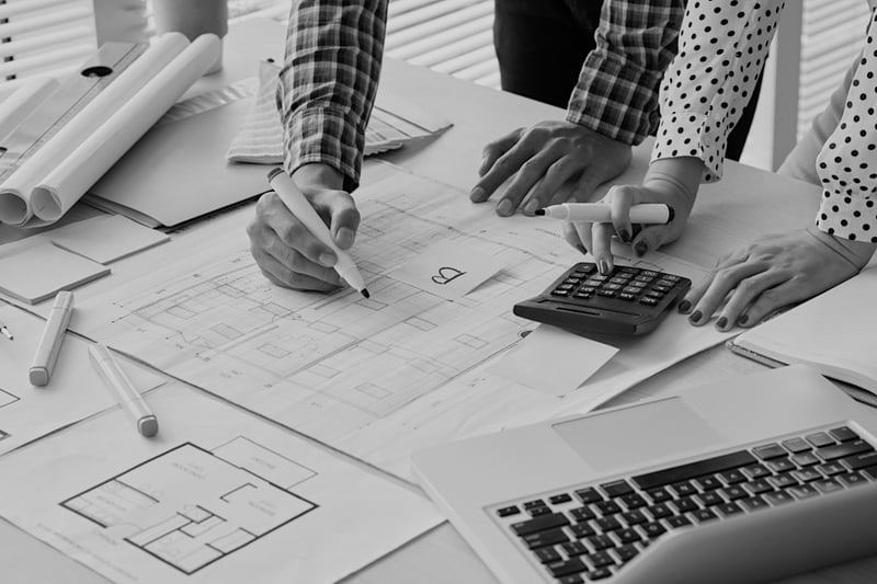 contractor man and woman with calculator and markers drawing on work documents