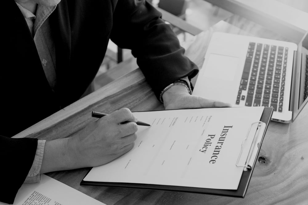 businessman at desk reviewing insurance policy on clipboard