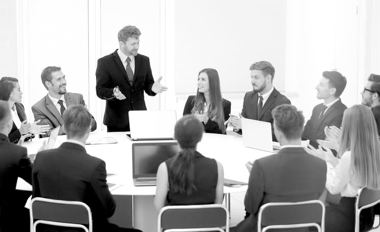 business meeting at round table with one man standing and explaining