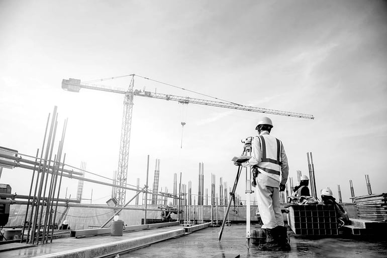 construction worker with hardhat filming at construction site with camera tripod