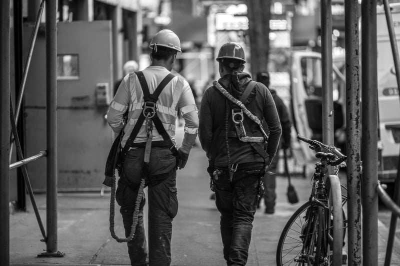 two construction workers with hardhats walking through the city