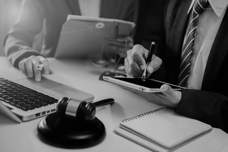 businessman at desk with tablet, laptop, notebook, and judge gavel