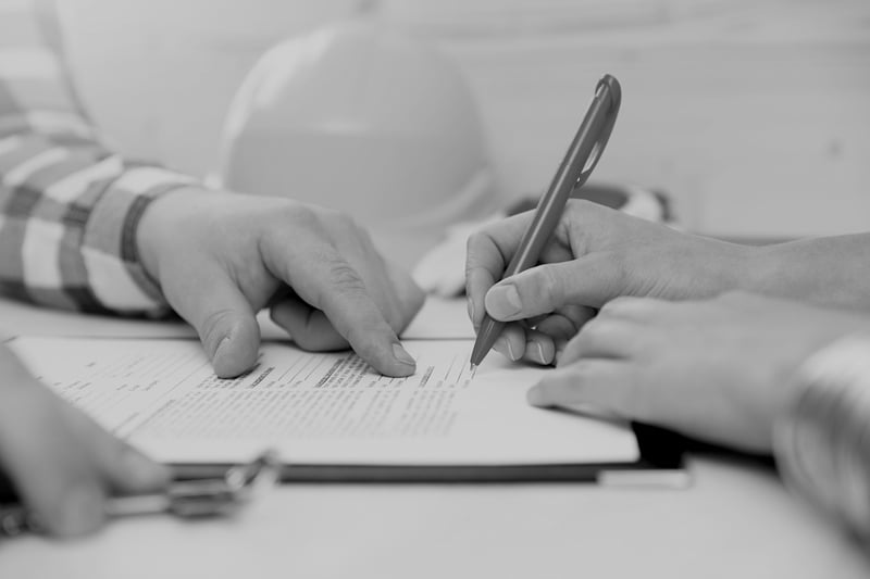 contractor signing construction document with hardhat on table