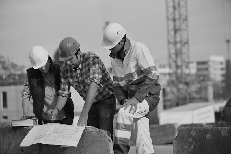 three construction workers at jobsite reviewing plans