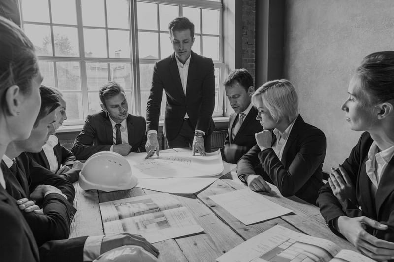 construction business meeting at wooden desk with hardhats and documents