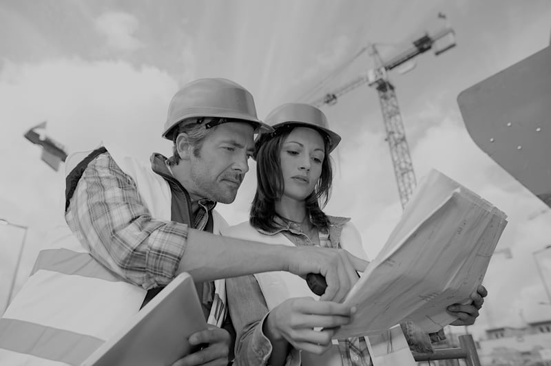 male construction worker showing worksite plans to female construction worker wearing hardhat