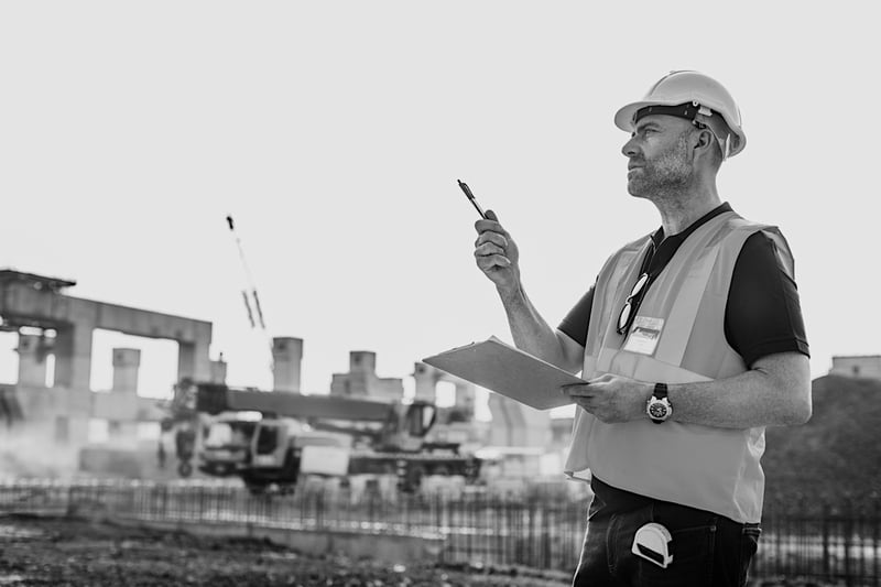 construction worker outside with clipboard and pen evaluating work site