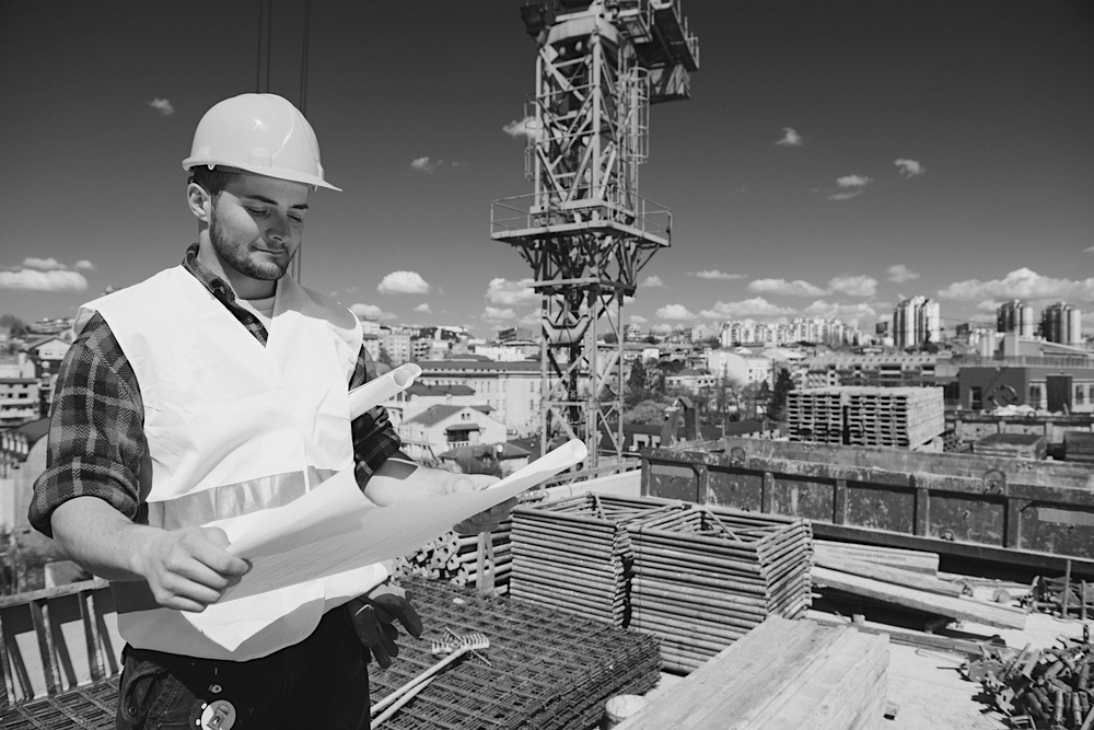 male construction worker with hardhat and uniform reviewing construction plans at jobsite