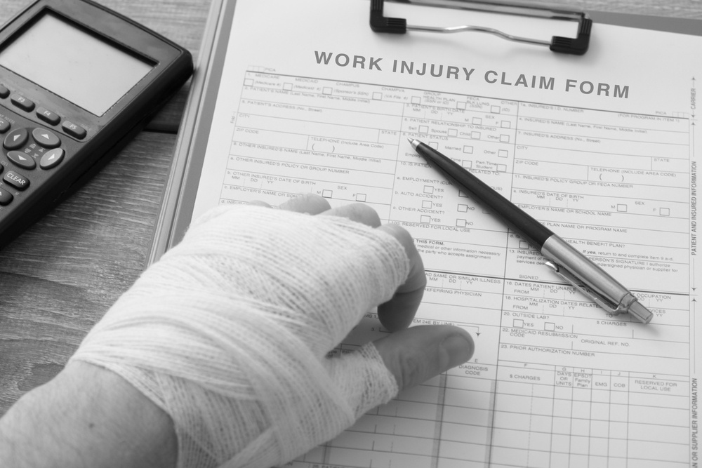 injured hand with bandages resting on desk with work injury claim form