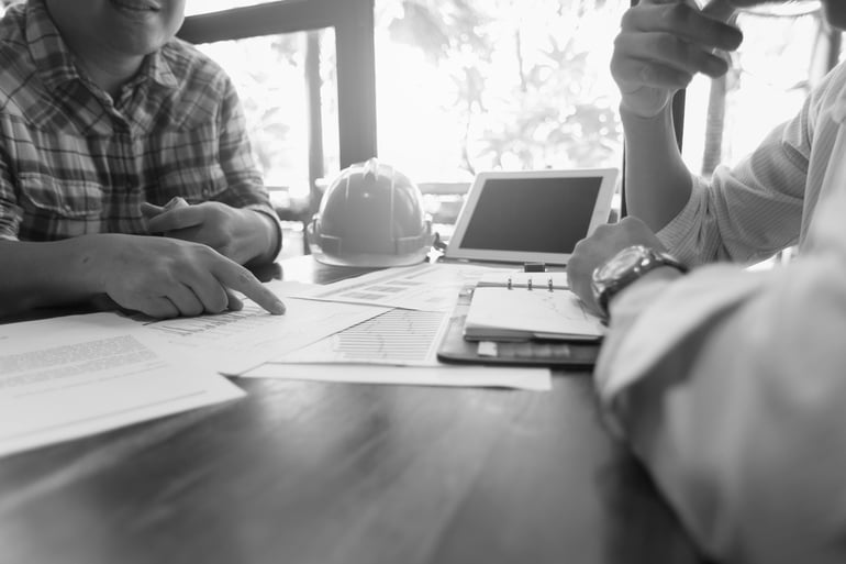 construction worker explaining OCIP and CCIP information to a coworker at a desk