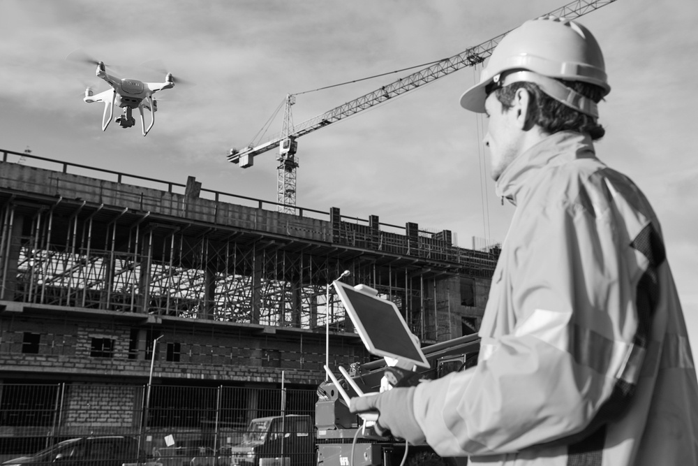 construction worker with hardhat flying a drone near a construction site