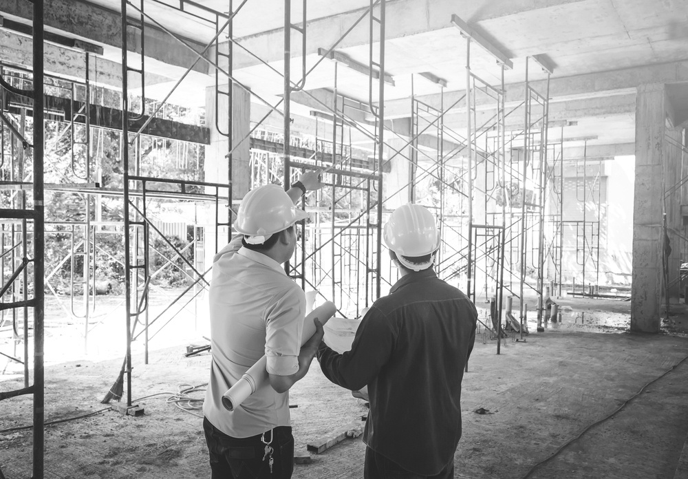 two construction workers with hardhats investigating jobsite for construction risks