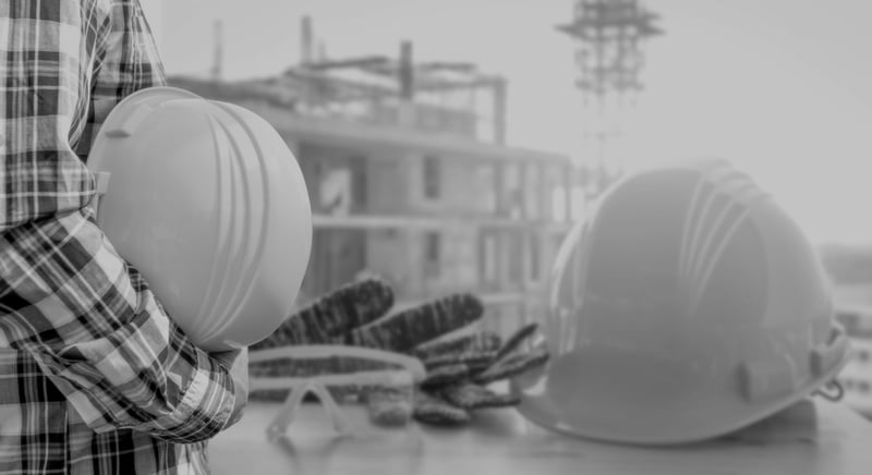 construction worker holding hardhat close while outside at construction site