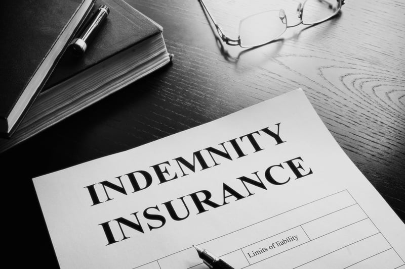 indemnity insurance form on wooden desk with books and glasses