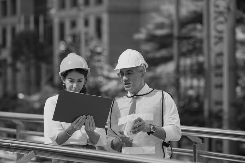 female contractor with hardhat reviewing design plans with male contractor with hardhat
