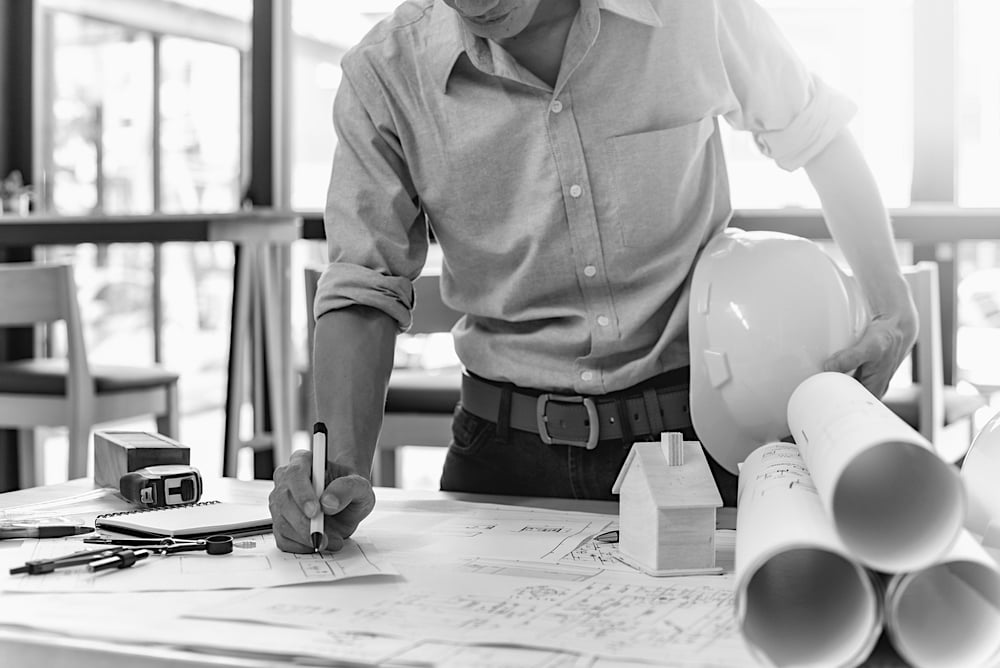 construction worker holding hardhat and writing job plans at a desk