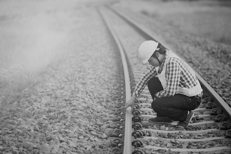 construction worker on railroad tracks observing stability of rails