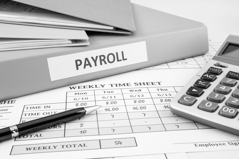 payroll binder and weekly time sheet  on desk with pen and calculator