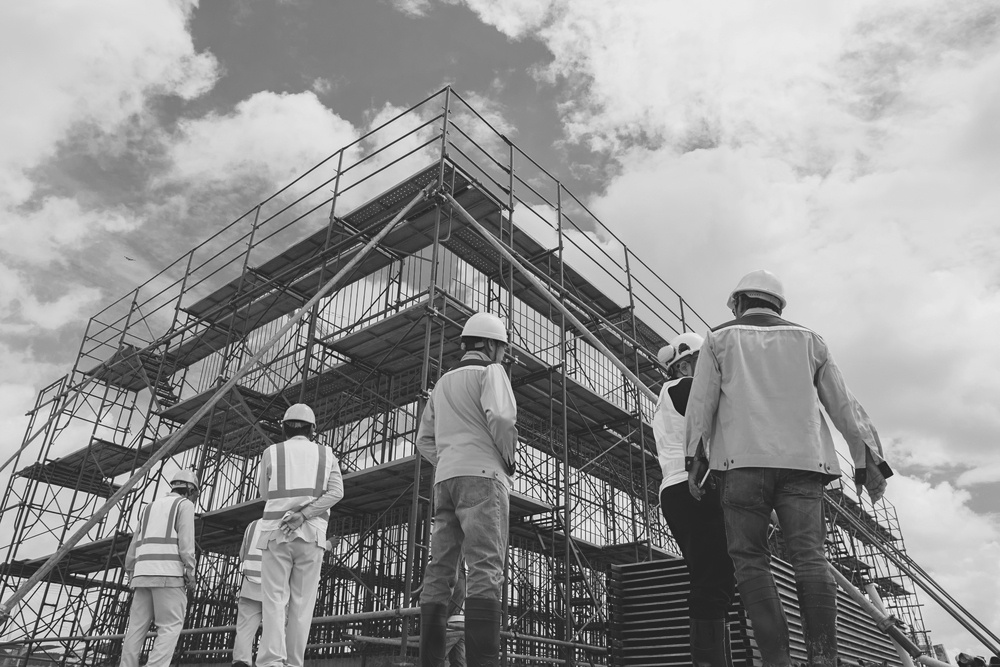 team and construction workers observing construction jobsite outside