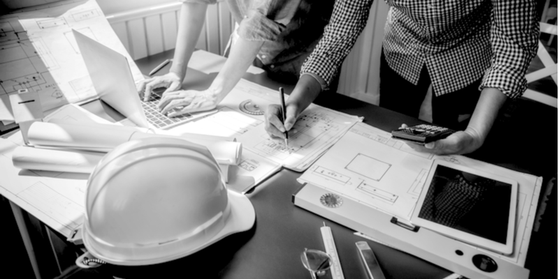 Construction workers financial planning at laptop on desk with a hard hat