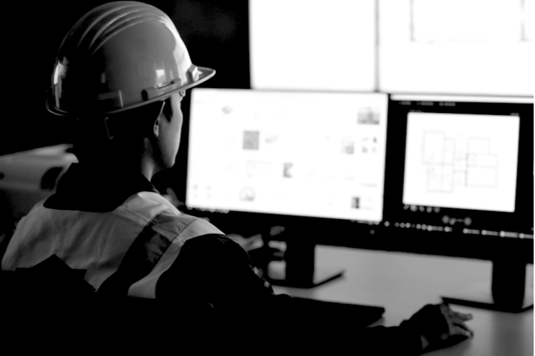 Construction worker at office with 2 desktops