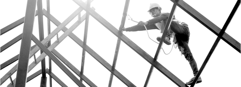 construction worker climbing a glass ceiling with safety harness at a jobsite