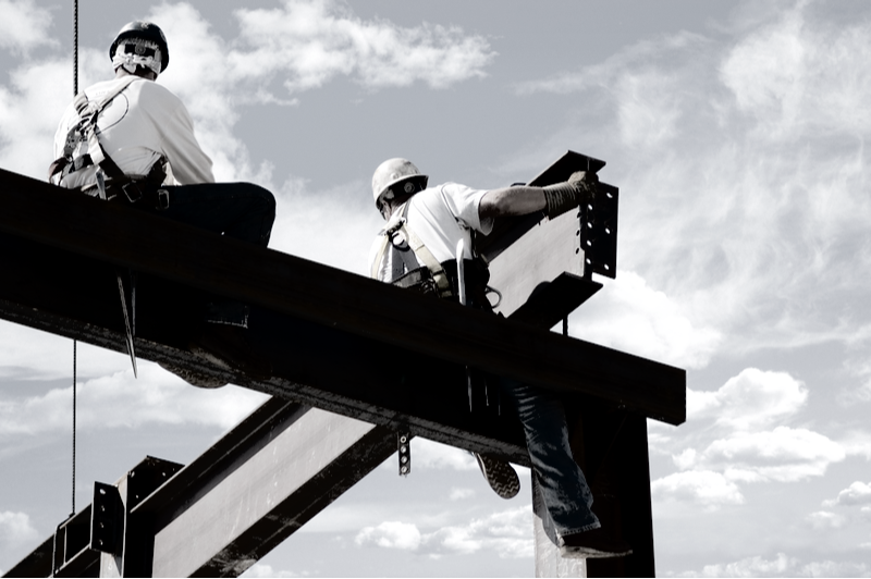 two contractors installing an i beam without safety gear