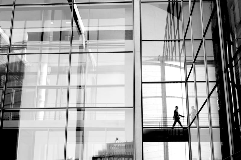 person walking in tall office building with many glass windows