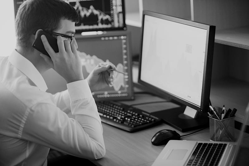 business man on cell phone in front of computer desktop