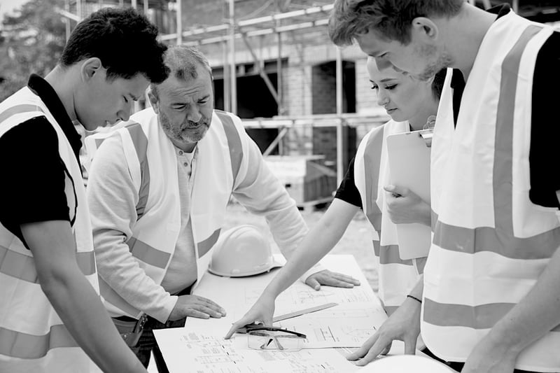 four construction workers reviewing work documents outside near worksite