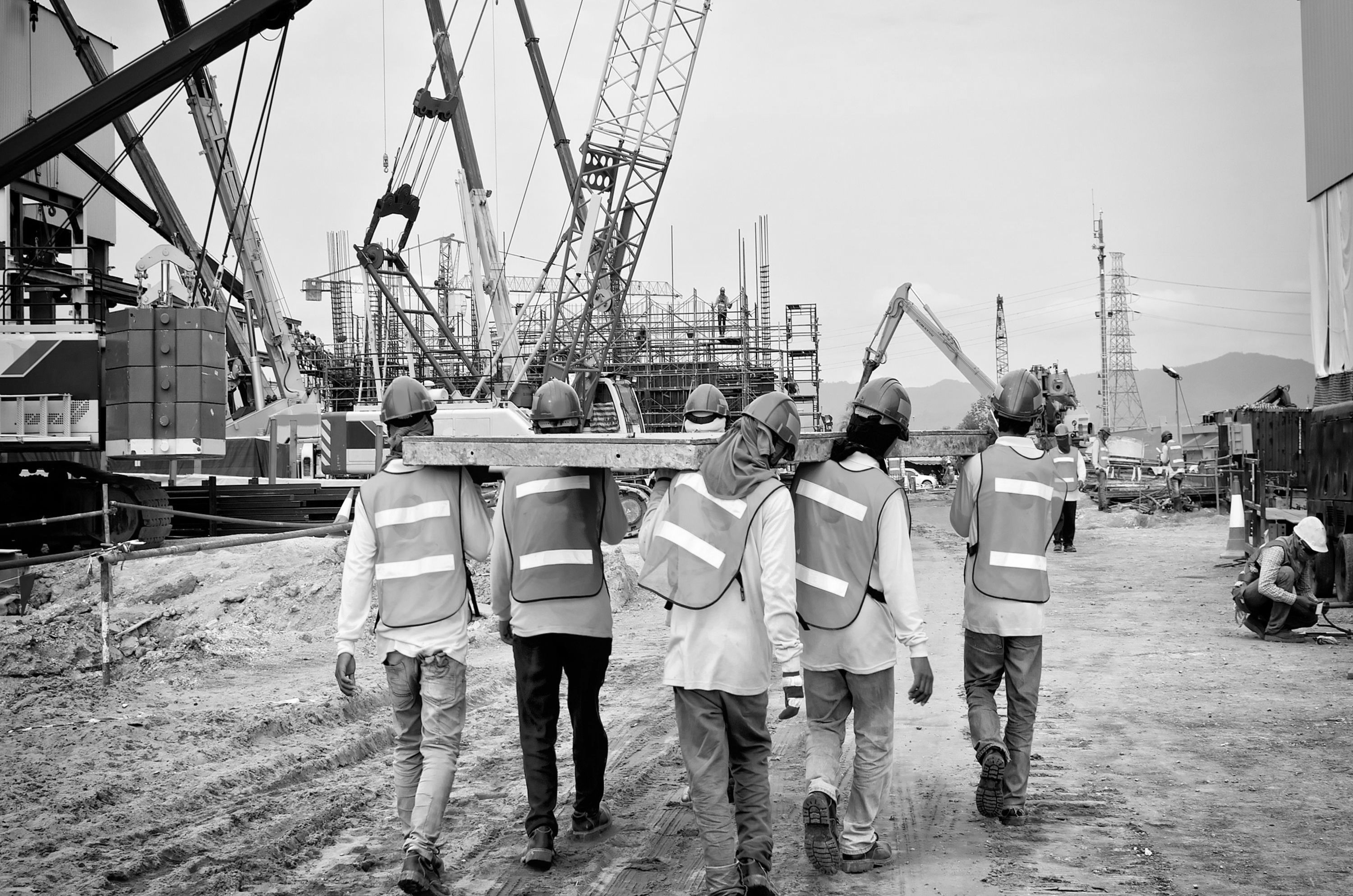 group of construction workers carrying a plank of wood in construction site.
