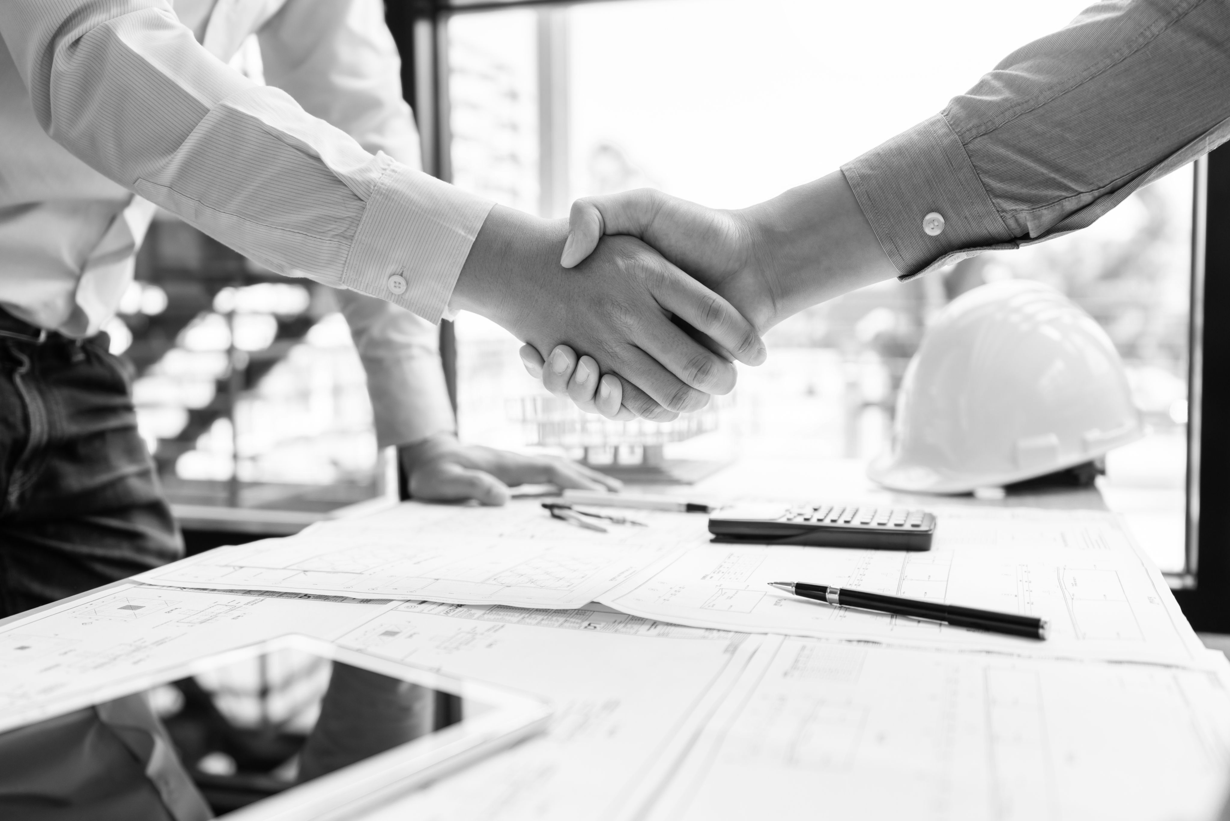 Architect and engineer construction workers shaking hands while working for teamwork and cooperation concept after finish an agreement in the office construction site, success collaboration concept