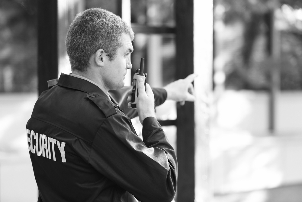 security officer in uniform holding walkie talkie and pointing