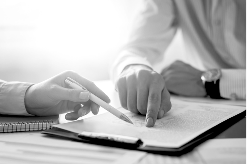 Business people negotiating a contract. Human hands working with documents at desk and signing excess liability contract.