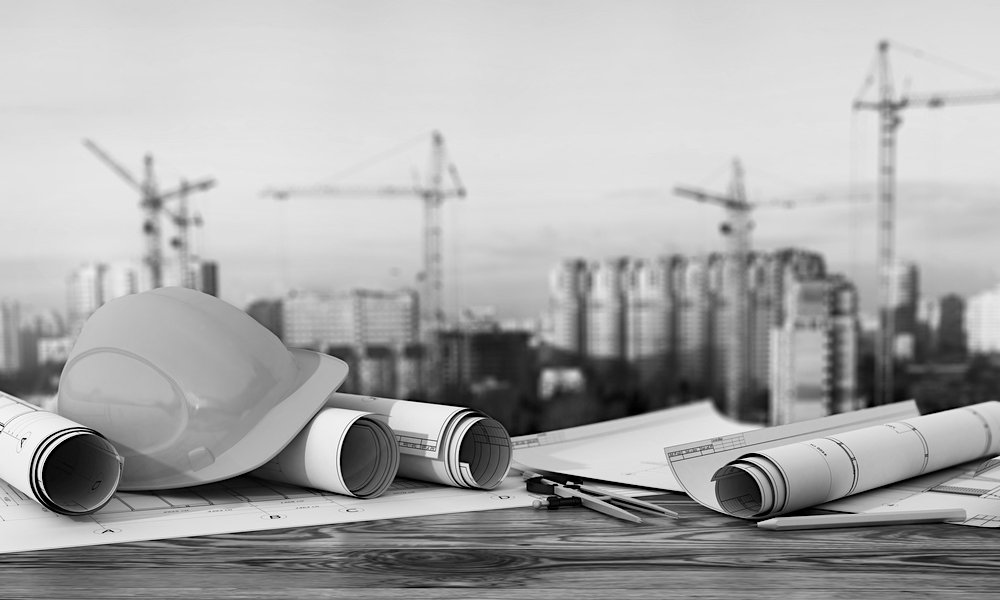 Project plans on a table with a hard hat and construction in the background.